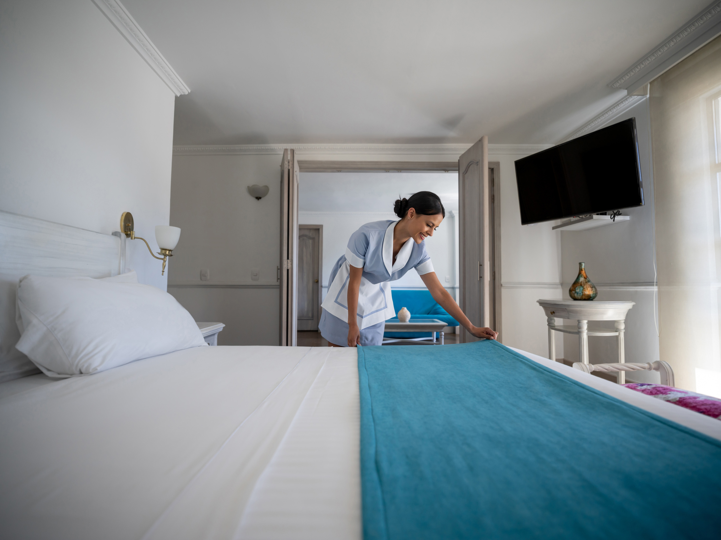 Housekeeper working at a hotel doing the bed